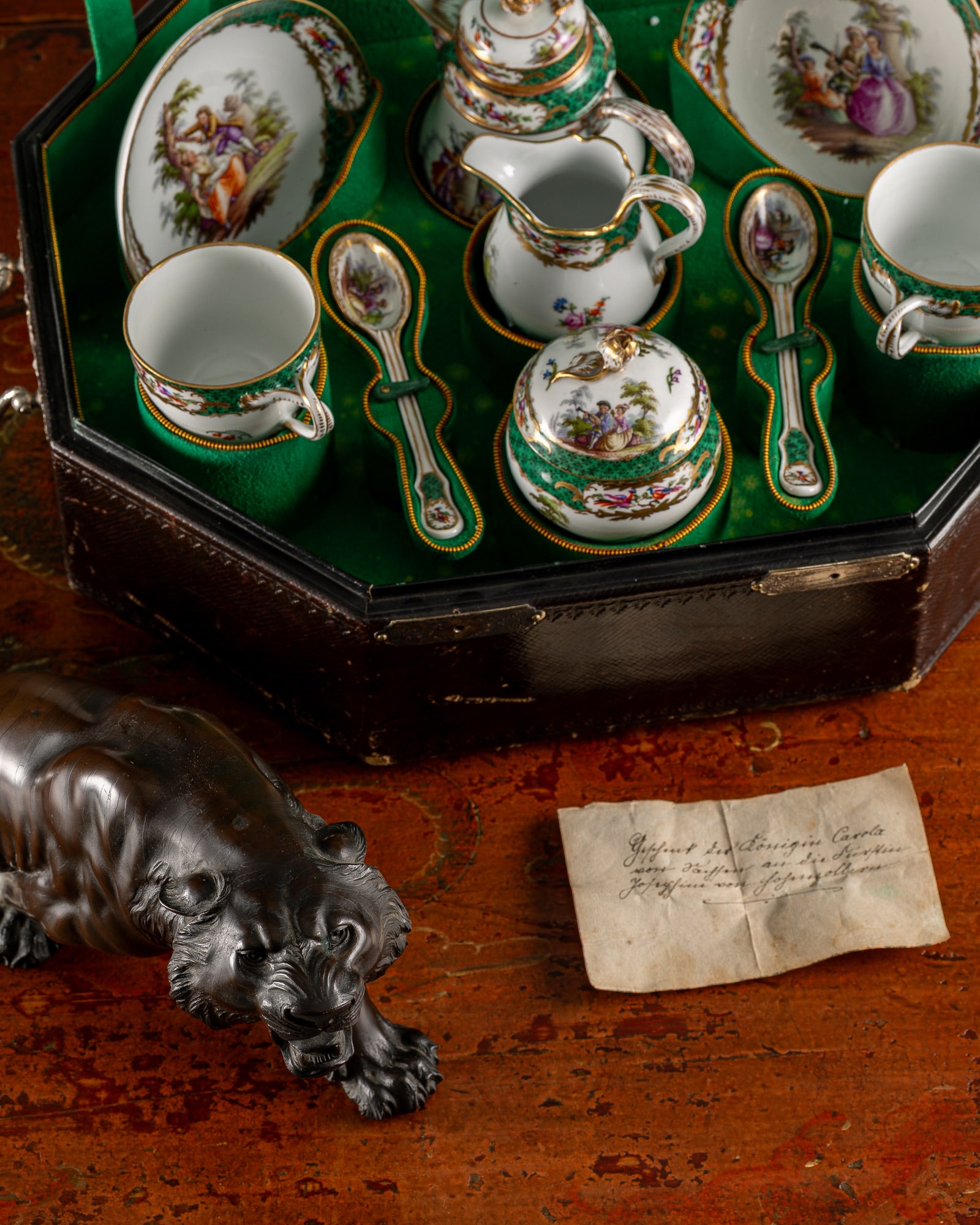 Tête-à-Tête aus Meissener Porzellan im Koffer, davor ein Tiger aus Bronze und eine handschriftliche Notiz
